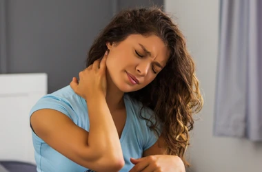 A young woman touching her neck and grimacing in pain after a personal injury