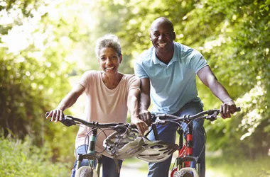 A couple biking together down a wooded path